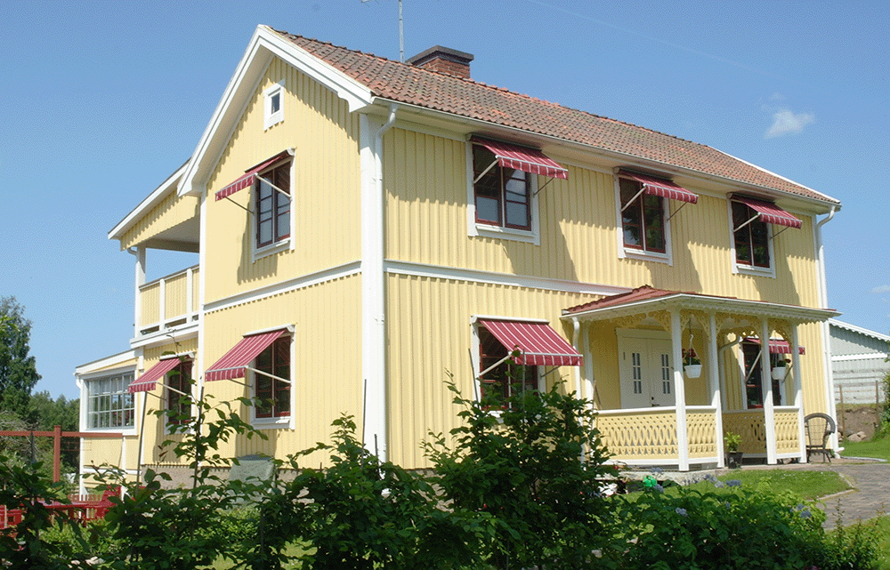 Vinröda markiser i fagersta på ett gult trähus.